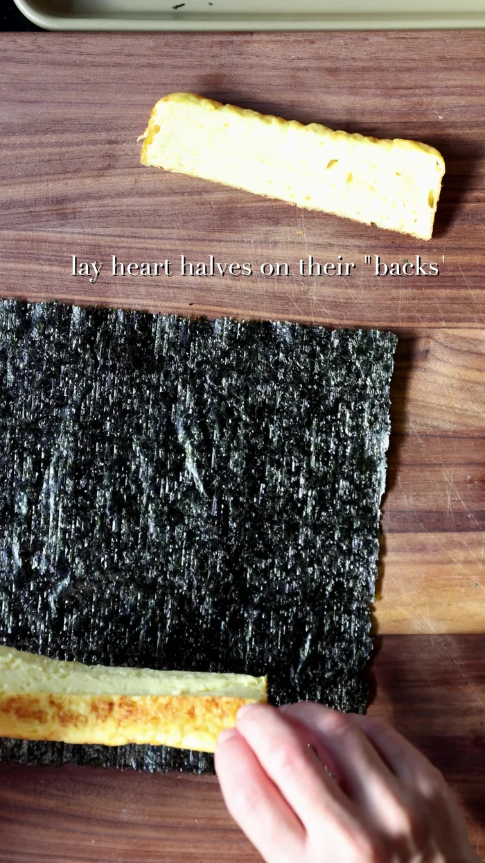 Cut a standard-sized nori sheet to fit around the heart-shaped omelette, leaving about an inch on top and bottom. Fill the V-shaped space at the top with rice. Place the heart-shaped omelette (with rice) in the center of the seaweed sheet, then spread rice to the top 80-90%.