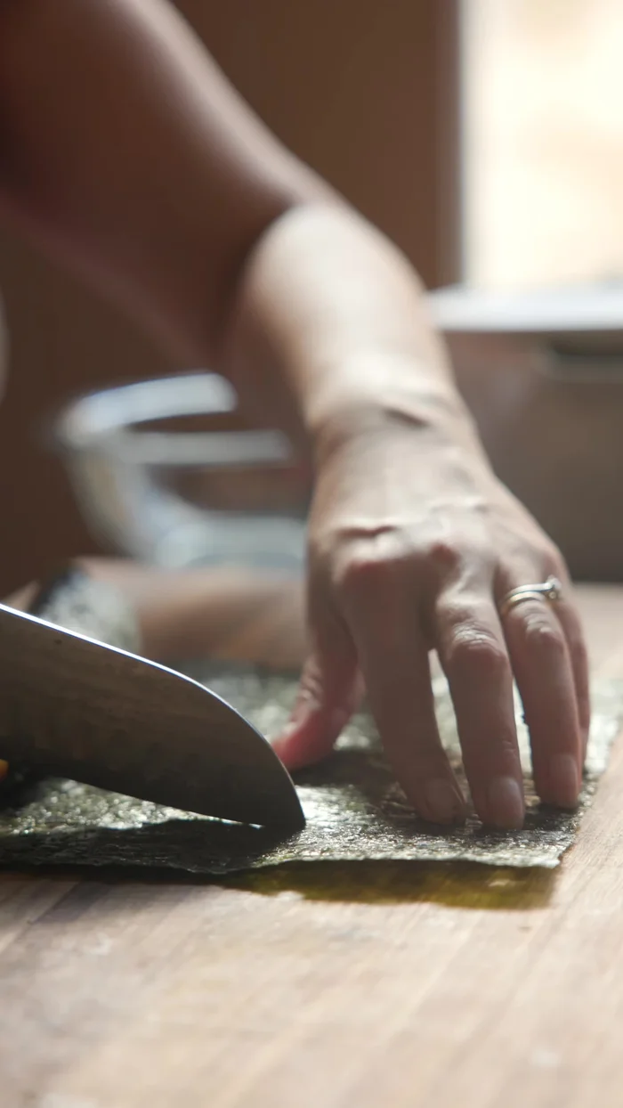 Roll the Heart Kimbap tightly, drizzle with sesame oil, and cut into 1/2-inch thick pieces.