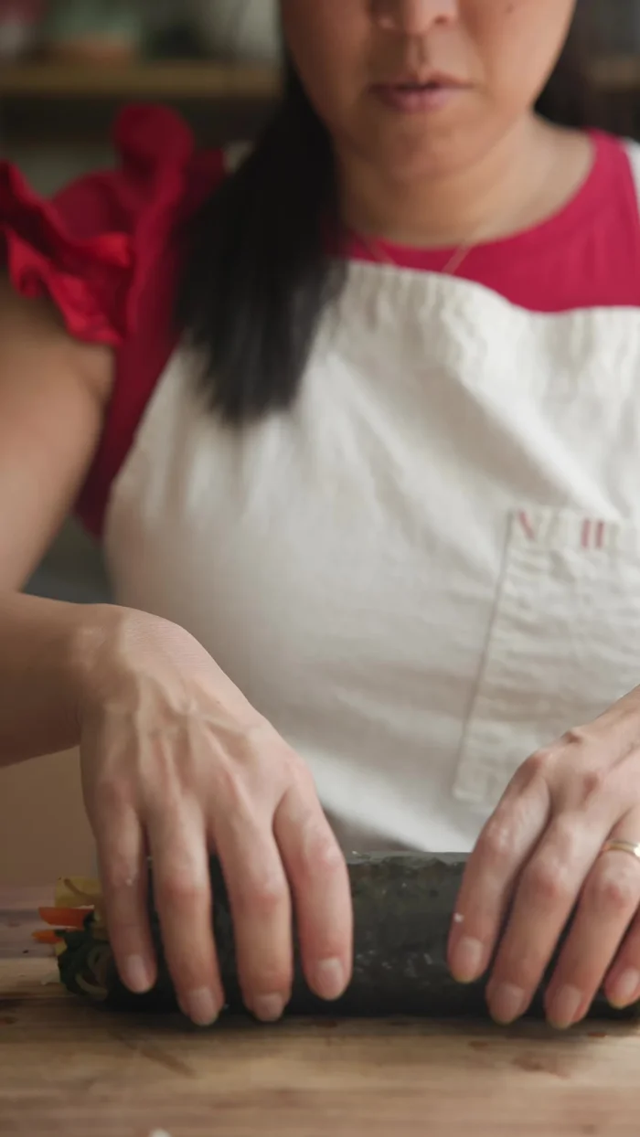 Roll the Chunky Kimbap tightly, drizzle with sesame oil, and cut into 1/2-inch thick pieces.