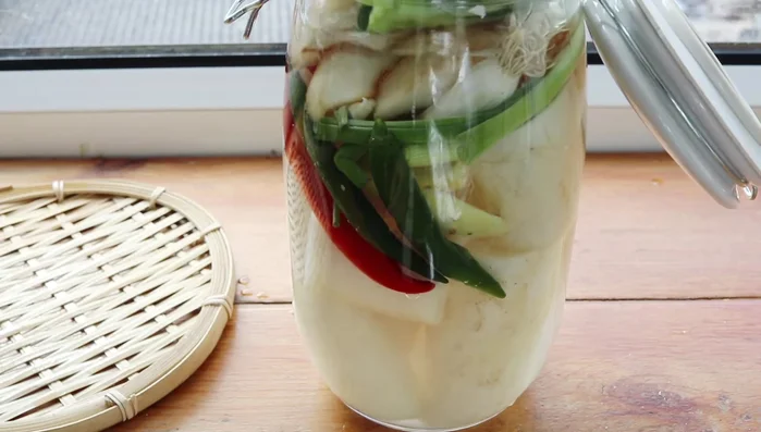 Fill the container with water, almost to the top. Add more mustard greens on top. Use a weight to keep everything submerged (optional).