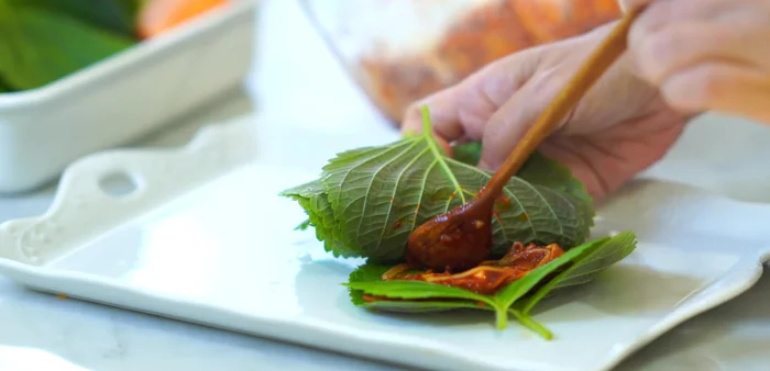 Arrange 9-10 perilla leaves on a plate. Add about half a teaspoon of the seasoning mixture onto each leaf and spread it roughly.