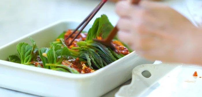 Transfer the seasoned leaves into a container. Pour 1/4 cup of water into the empty bowl, wash off the remaining seasoning, and pour it over the perilla leaves.