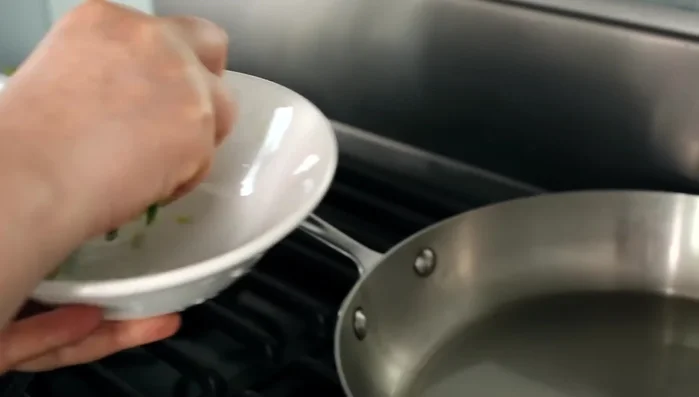 Heat the cooking oil in a frying pan over medium-high heat. Add the garlic scapes and stir-fry for 1 minute. Then stir occasionally until tender (323.479).