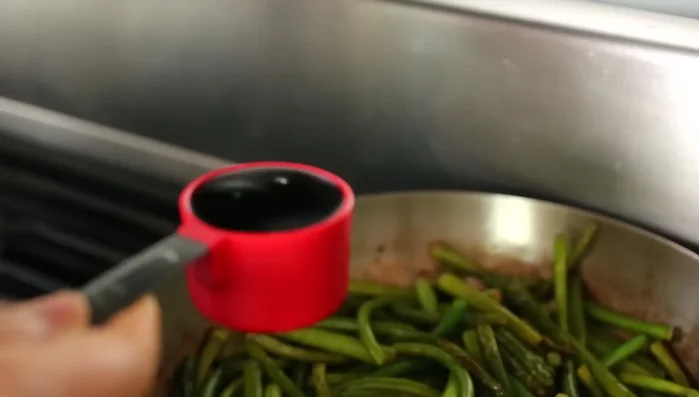 After about 7 minutes of stir-frying, add the soy sauce. Stir to coat. Reduce the heat to medium (405.12).
