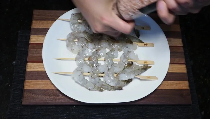Season shrimp with salt and pepper, pressing the seasonings into the shrimp on both sides. [109.2]