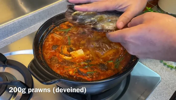 Add prawns, baby octopus, clams, and enoki mushrooms. Increase heat to high and bring to a boil.