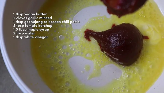 For the glaze, melt vegan butter in a small saucepan. Add minced garlic, gochujang, tomato ketchup, maple syrup, water, and white vinegar. Simmer until thickened. (123.479)