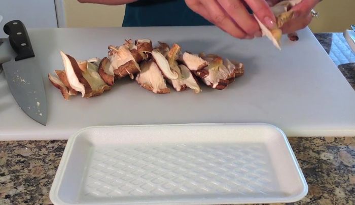 Slice all vegetables: shiitake mushrooms, zucchini, garlic, carrots, and white onion.