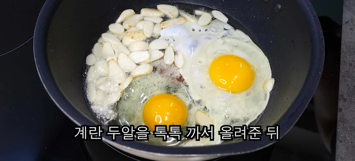 Crack two eggs onto the garlic and shake them to make scrambled eggs.