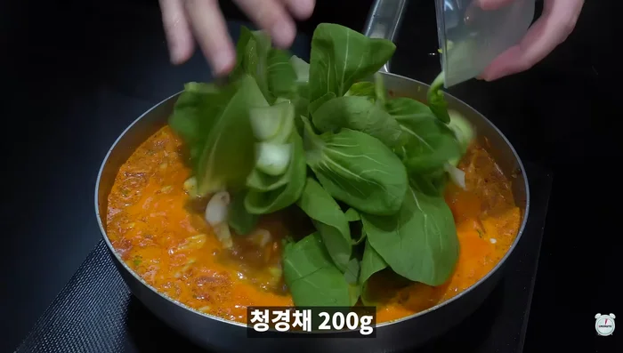 Add chicken tok and pork bone powder. Add fire sauce, Hyogo mushrooms, bok choy, zucchini, Cheongyang pepper, seafood mix, seasoned salt, and pepper.