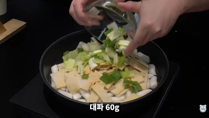 Add panne water, rice cake, fish cake, and green onion to a pot. Then, add two large spoons of red pepper powder, red pepper paste, sugar, and syrup, and half a spoon of MSG and dasida.