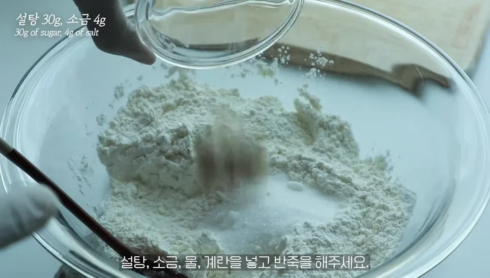 Add sugar, salt, water, and eggs to the bowl and knead until a dough lump forms.