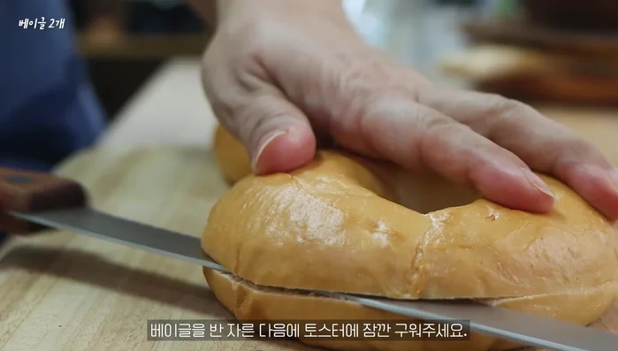 Grind the bagel in half and toast it briefly in a toaster.