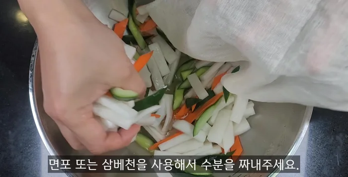 Squeeze excess moisture from the marinated radish, cucumber, and carrots. Combine with golbaengi, water parsley, and seasoning sauce. Add sesame seeds and mix well.