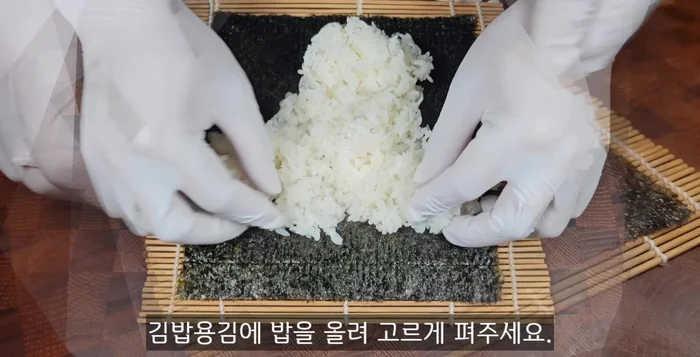 Place seasoned rice on the seaweed, leaving 2-3cm space at the top. Add burdock, radish, stir-fried fish cakes, and stir-fried carrots.