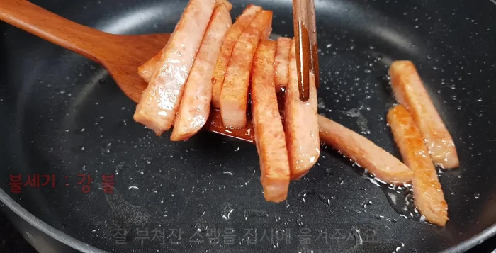 Remove the cooked Spam and set it aside. Add the sliced onions to the remaining oil in the pan and stir-fry for about 30 seconds.