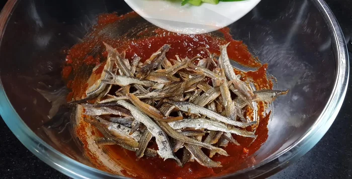 Add stir-fried anchovies and blanched green onions to the seasoning. Mix well. Sprinkle with sesame seeds and mix again.