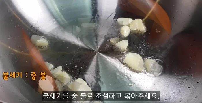Heat oil in a wok. Fry sliced garlic until fragrant. Add anchovies and chili peppers. Fry until fragrant.