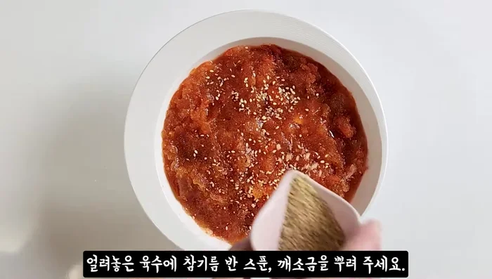 Assemble the noodles: Place noodles in a bowl. Add kimchi, sesame oil, and sesame salt. Add the frozen broth, cucumber, and boiled egg.