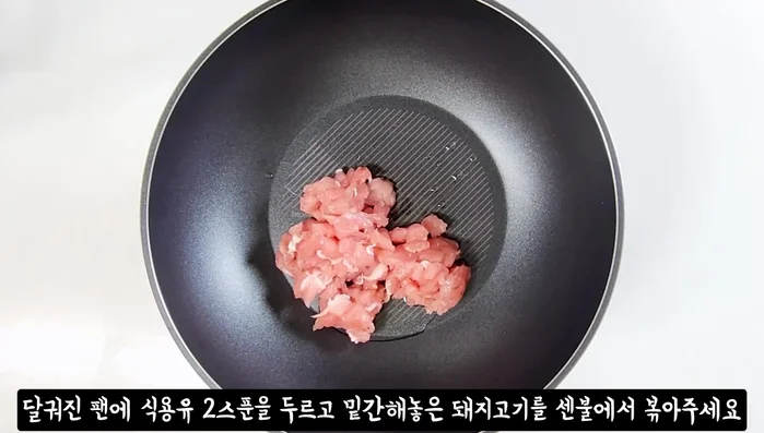 Heat oil in a pan. Stir-fry pork until half-cooked. Add minced garlic and stir-fry.