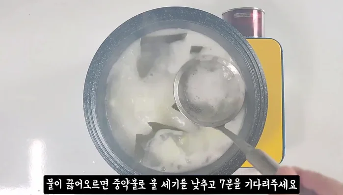 After 7 minutes of boiling, remove kelp and add soybean paste, red pepper paste, and broth. Lower heat to medium.