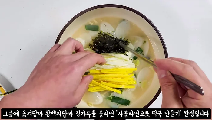 Transfer the tteokguk to a bowl, top with the sliced jjidan, and sprinkle with laver powder.