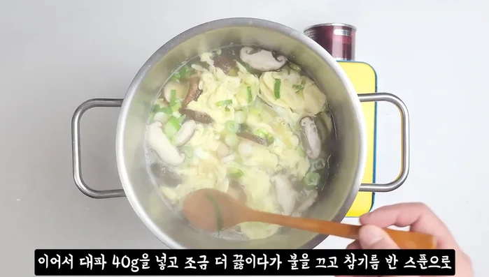 Add green onions, simmer briefly, then turn off the heat. Finish with sesame oil.