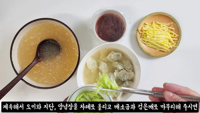 Assemble the soup: Mix the moisture from the drained cucumbers into the broth. Pour the cold broth over the drained dumplings in a bowl. Add the cucumber, egg yolk, sesame salt, and black sesame seeds.