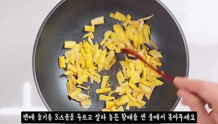 Heat sesame oil in a pan and stir-fry the dried pollack over high heat until coated.