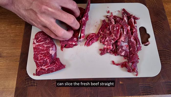 Prepare the beef: If your knife skills are good, slice the beef thinly. If not (like the video's host), roughly chop it to make it easier to cut.
