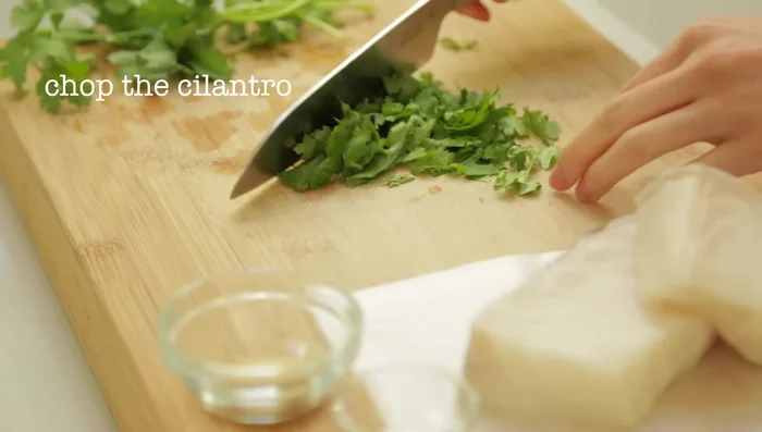 Coarsely chop the cilantro. Rinse sea bass fillets under cold water, pat dry, and brush with oil. Sprinkle with garlic powder, sea salt, and cilantro; marinate for 10 minutes.