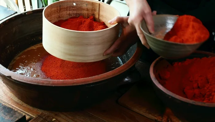 Add red pepper powder (ensure it's well-drained to prevent clumping). Adjust the consistency with water as needed.