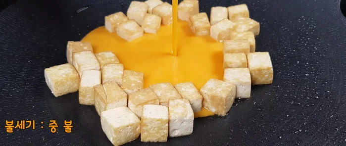 Push the tofu to the edge of the pan and pour the egg mixture into the center. Stir slowly to make the egg larger than the tofu.