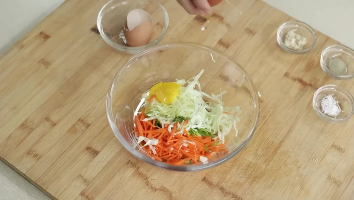 In a bowl, combine the sliced vegetables, eggs, powdered chicken broth, salt, and pepper.