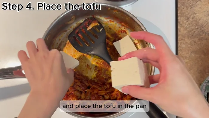 Add the tofu to the pan. Add 0.5-1 cup of water and 2 tablespoons of soy sauce.