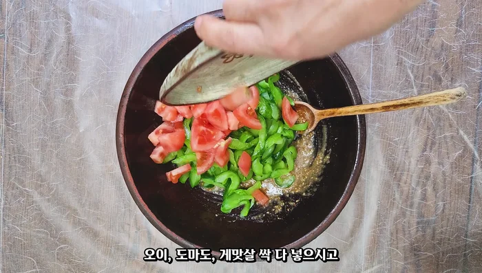 Add the drained cucumbers, tomatoes, and seaweed to the seasoning. Mix well to ensure the seasoning is absorbed.