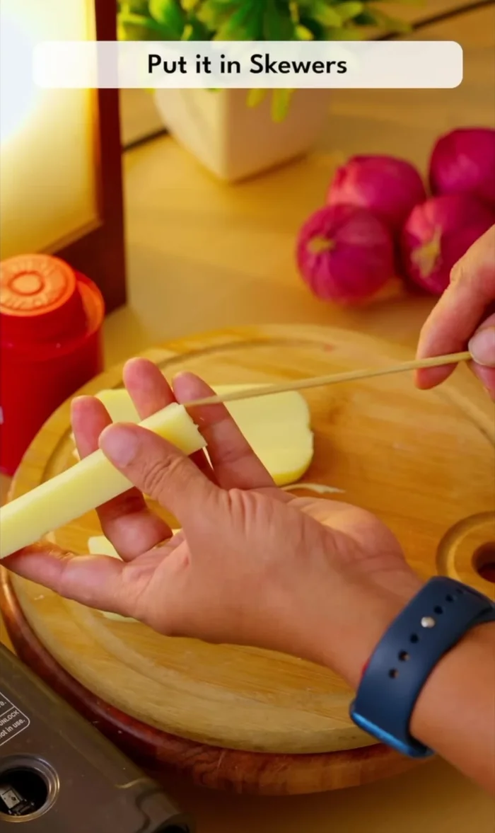 Assemble the corn dogs: Insert cheese sticks onto skewers.