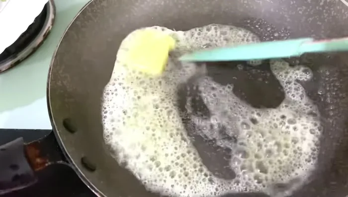 Melt butter in a frying pan over medium heat. Add 4 minced garlic cloves and sauté until lightly golden brown.