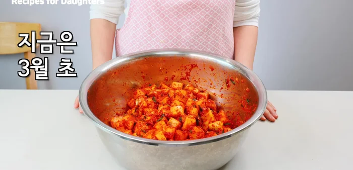 Pack the Kkakdugi in a kimchi container, placing a weight on top to keep it submerged.
