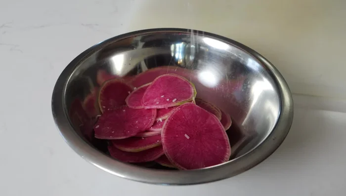 Prepare the watermelon radish: Thinly slice watermelon radish, season with salt and rice vinegar, and let it pickle for 45 minutes.