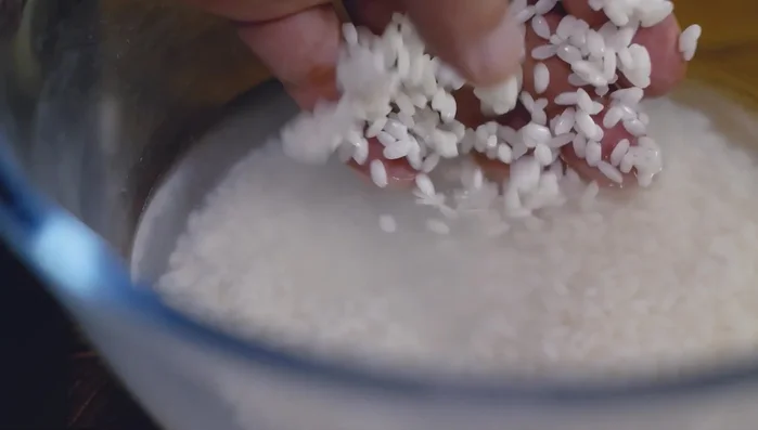 Check if the rice is well-soaked. Heat a pot, add sesame oil, and stir-fry the soaked rice for 3-5 minutes. Drain the rice using a strainer.