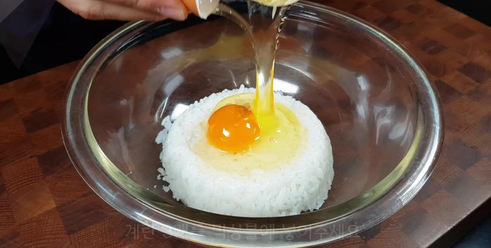 Place instant or plain rice in a mixing bowl. Crack three eggs into the bowl and add 1/2 teaspoon of salt.