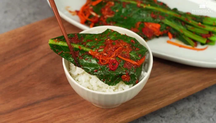 Combine kale and mixture: Add the prepared kale to the bowl and toss gently to coat the leaves evenly with the kimchi paste mixture. Ensure all leaves are coated.