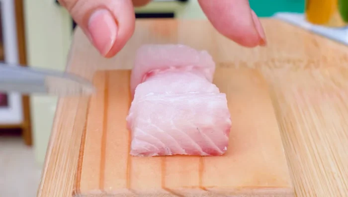 Cut fish meat into small pieces. Add garlic powder and mix.