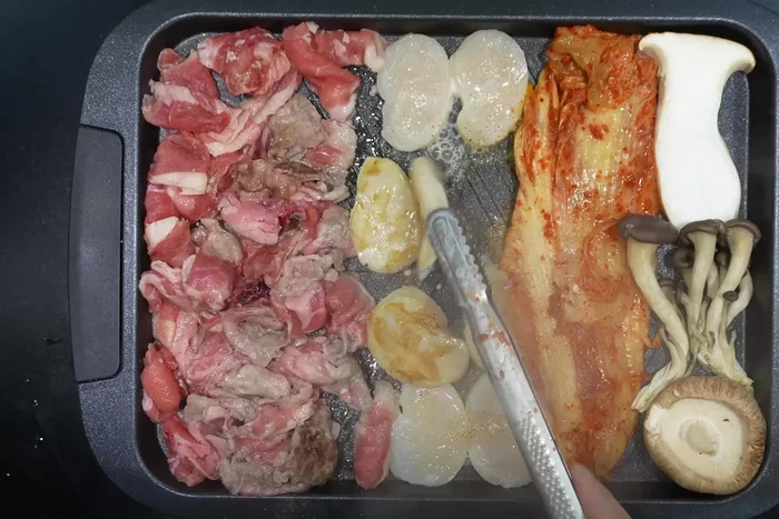Sprinkle the seasoning on the ingredients in the pan and fry them.