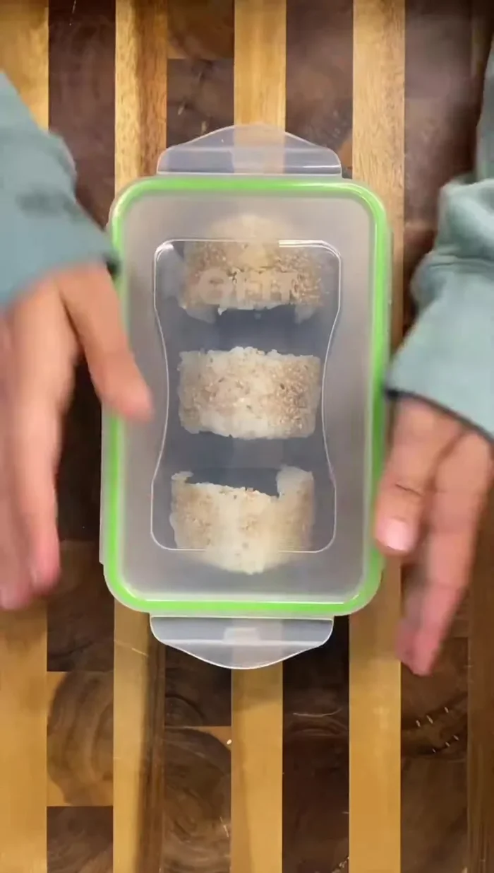 Pack the onigiri, Korean cucumber salad, and strawberries into a bento box.