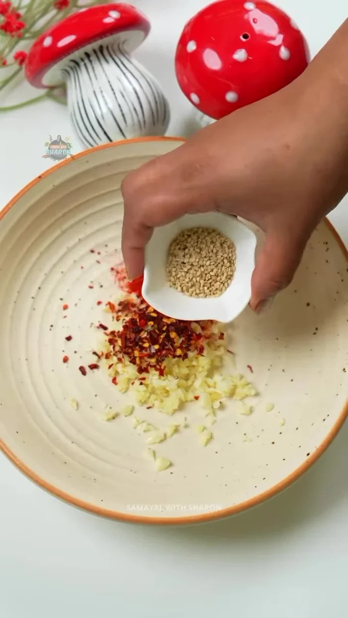 In a bowl, mix the chopped garlic and spring onions with 1 teaspoon each of chili flakes, chili powder, sesame seeds, and soy sauce.