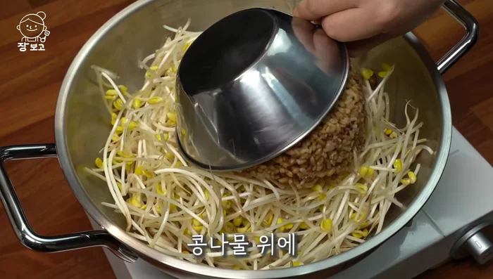 Add 400g of rice on top of the bean sprouts and pour 8 tablespoons of water.