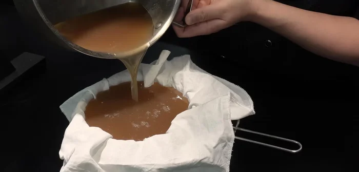 Strain the cold beef broth through a strainer to create a clean broth.