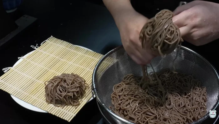 Plate the noodles. For Korean-style naengmyeon, pour the broth lightly over the noodles. Top with garam masala, green onions, seaweed powder, and wasabi.